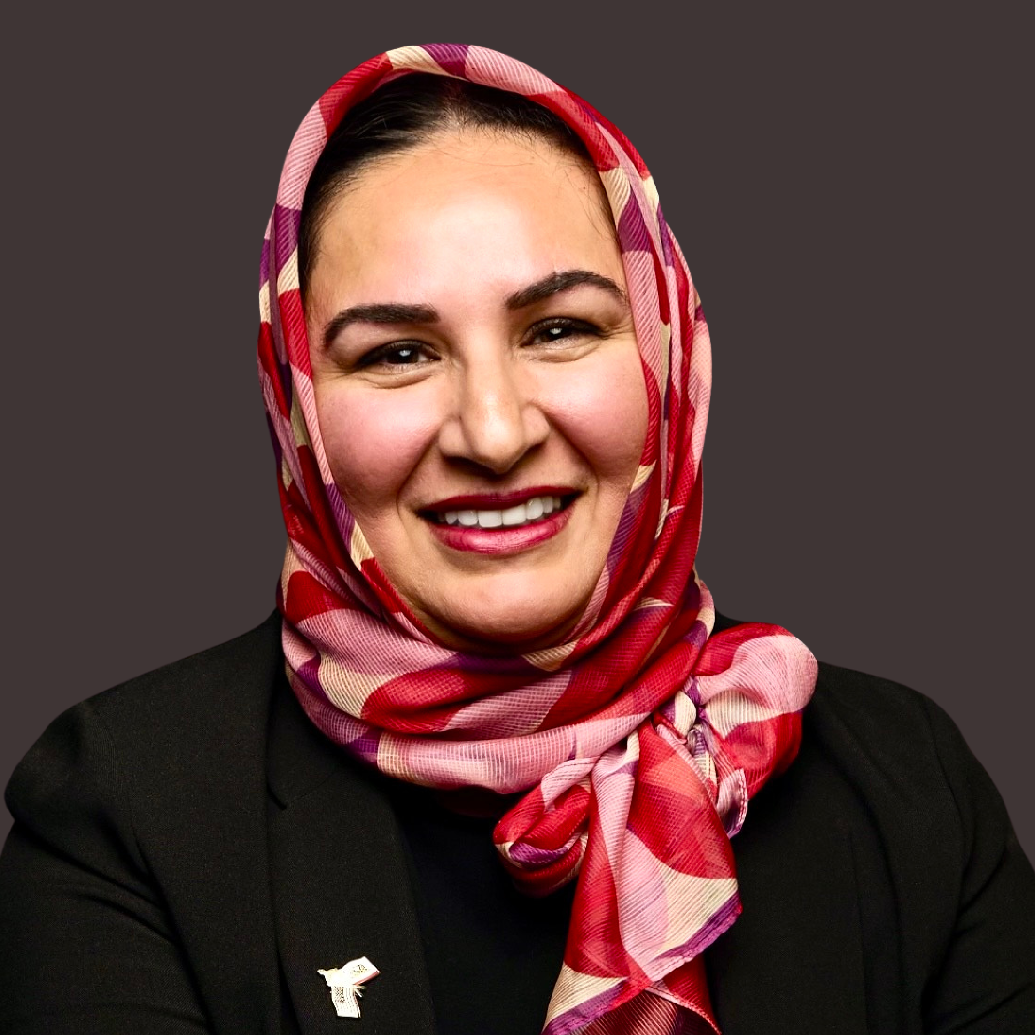 Tahra Goraya smiling in a red and rose patterned headscarf